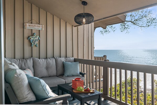 A cozy balcony with a sofa, a small table with fruit, and a 'WELCOME' sign.