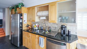 A modern kitchen with stainless steel appliances, wooden cabinets, and a tiled backsplash. - City Escape-Cottage by the Lake (Brampton)