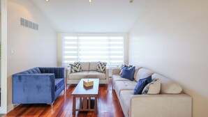 A living room with a blue sofa, a beige sofa, and a wooden coffee table. - City Escape-Cottage by the Lake (Brampton)