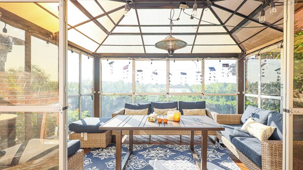 A conservatory with a table, seating, and a patterned floor. - City Escape-Cottage by the Lake (Brampton)