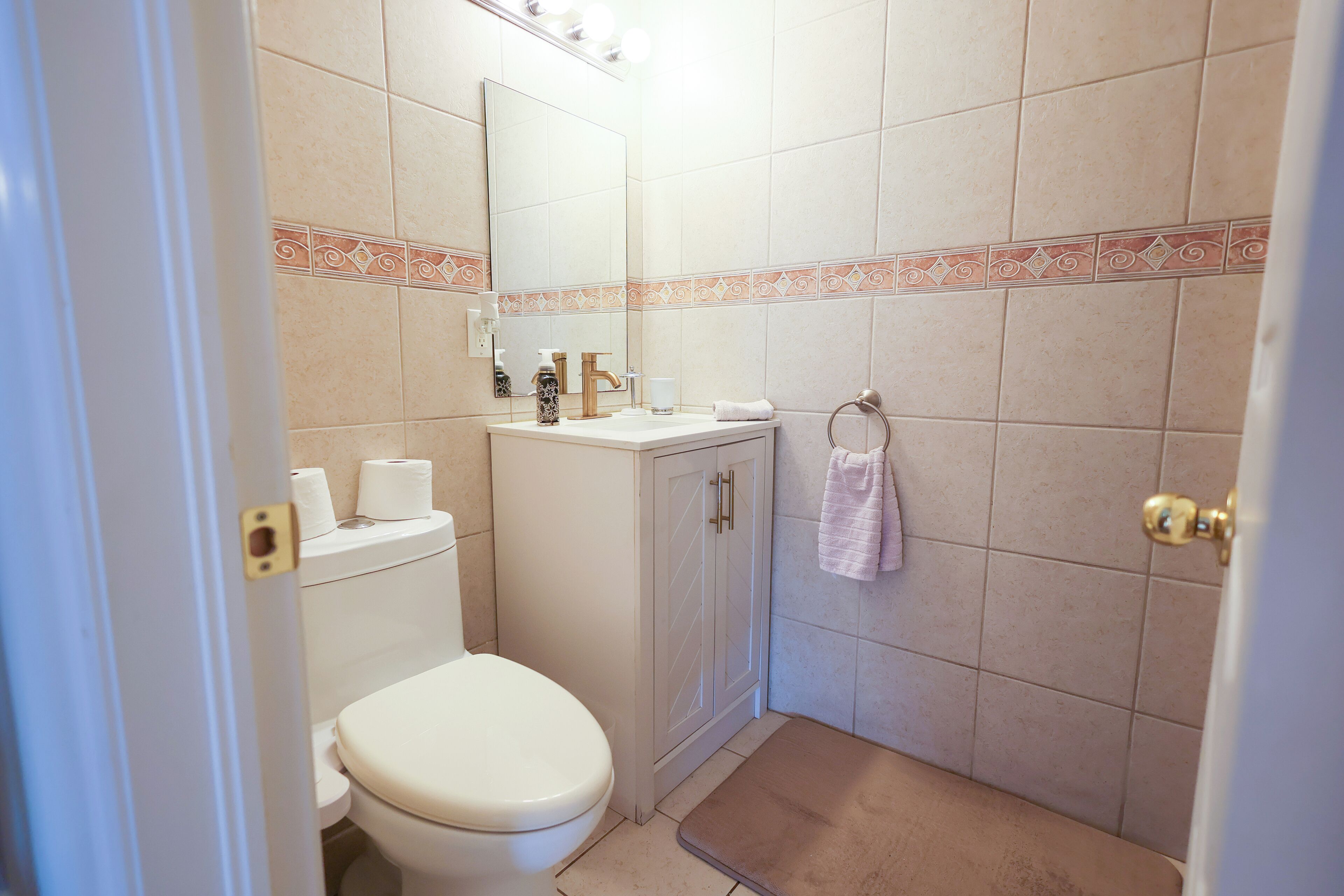 Een badkamer met toilet, wastafel, spiegel en douche.