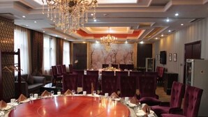 A conference room with a round table, red chairs, and a chandelier. - Jinshan Hotel (Harqin Banner)