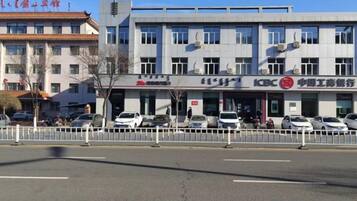 Un immeuble à plusieurs étages, doté d'une enseigne commerciale, d'un parking et d'une clôture blanche.
