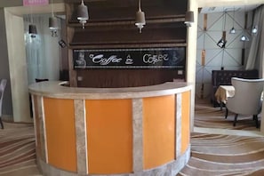 Zona d'entrada amb mostrador corbat, senyal amb motius de cafè i un disseny de moqueta.