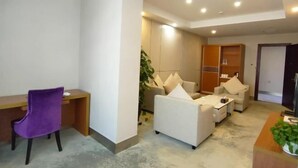 A modern living room with a desk, a purple chair, a sofa, and a coffee table. - Jinshan Hotel (Harqin Banner)