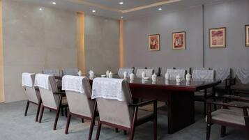 A conference room with a long table and chairs, white tablecloths, and framed pictures on the wall.