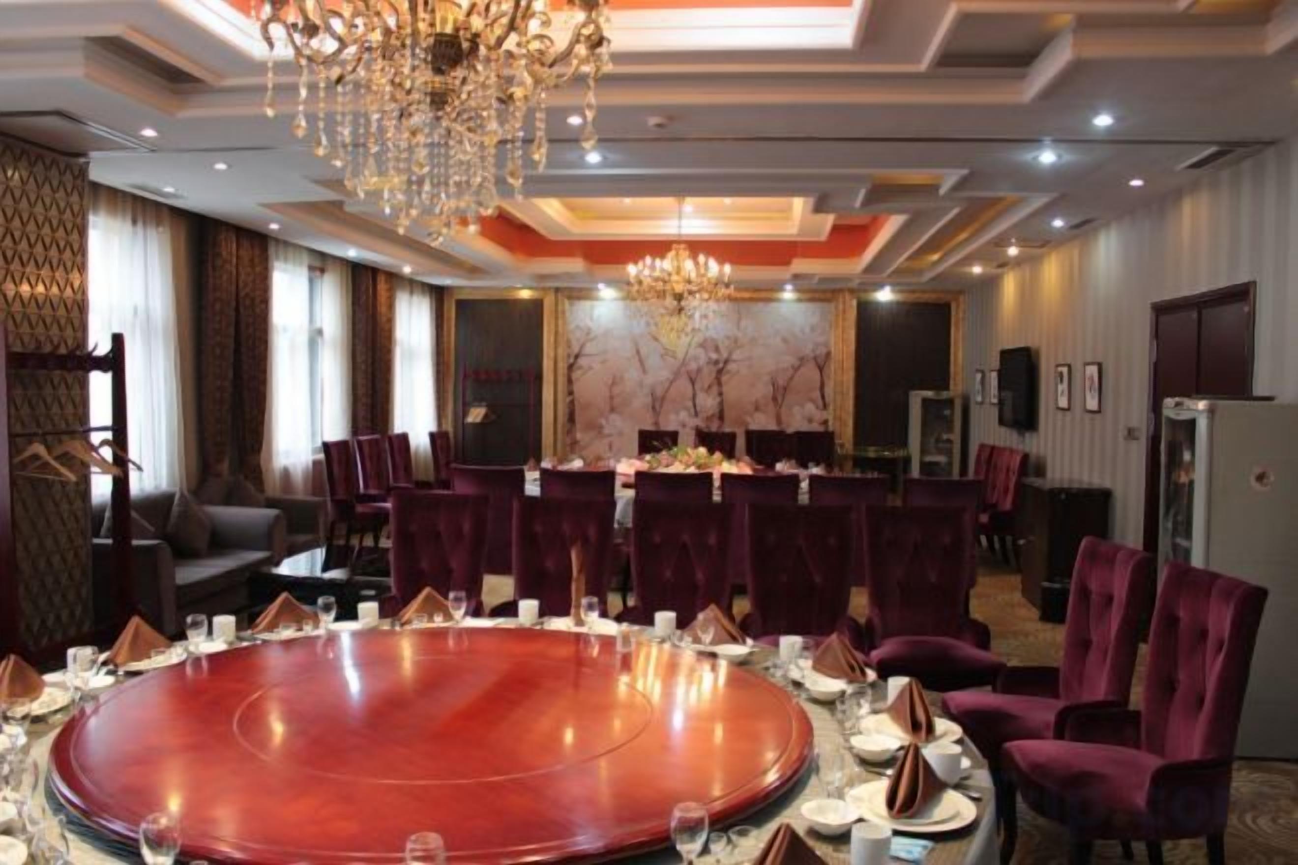 A conference room with a round table, chairs, and a chandelier.