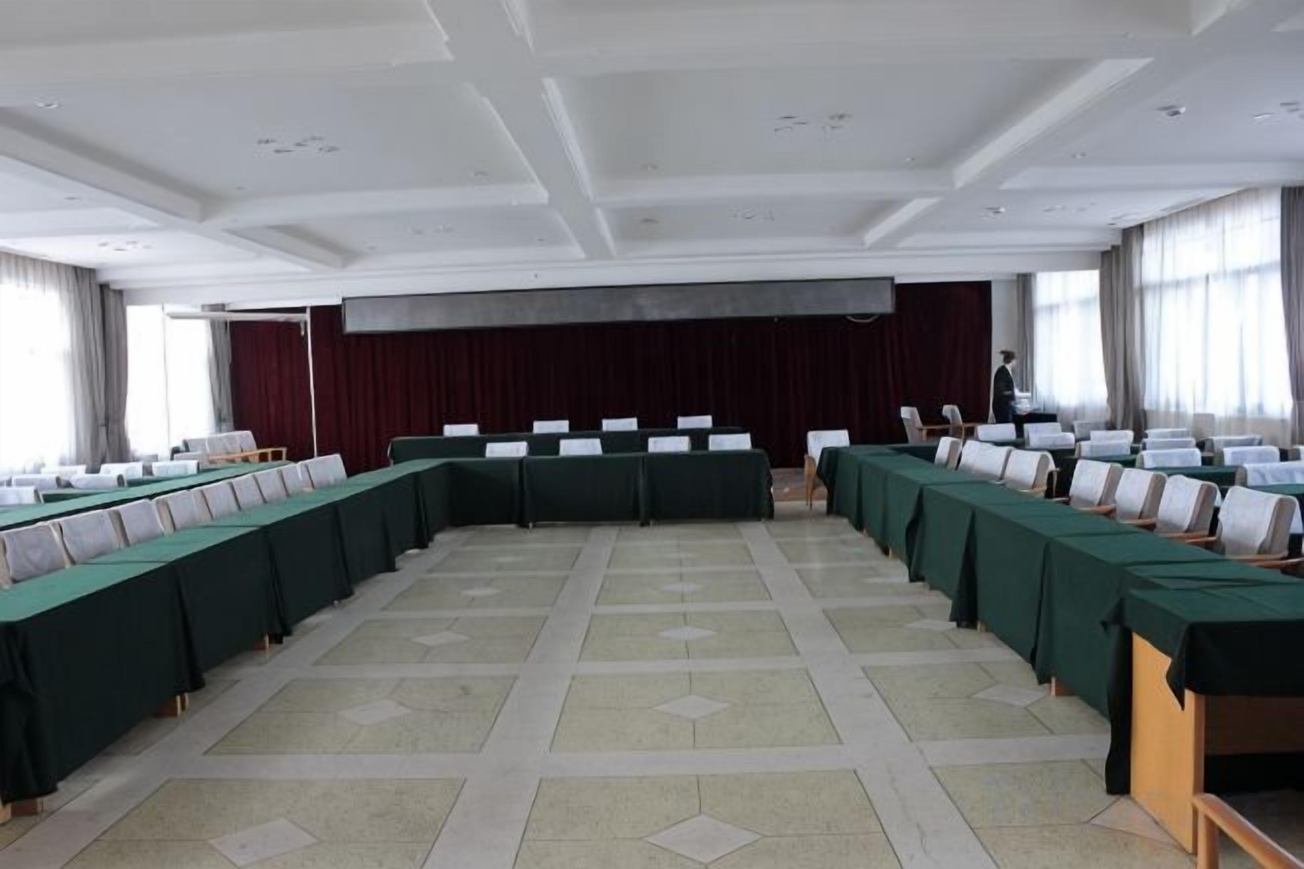 Una sala de conferències amb una taula llarga, cadires i una zona d'escenari.