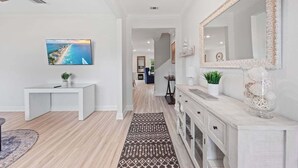 A modern interior with a white console table, a large mirror, and a patterned rug. - 14 Beds | Sleeps 16 | Piper Cove Retreat | Pool | Santa Rosa Beach (Santa Rosa Beach)