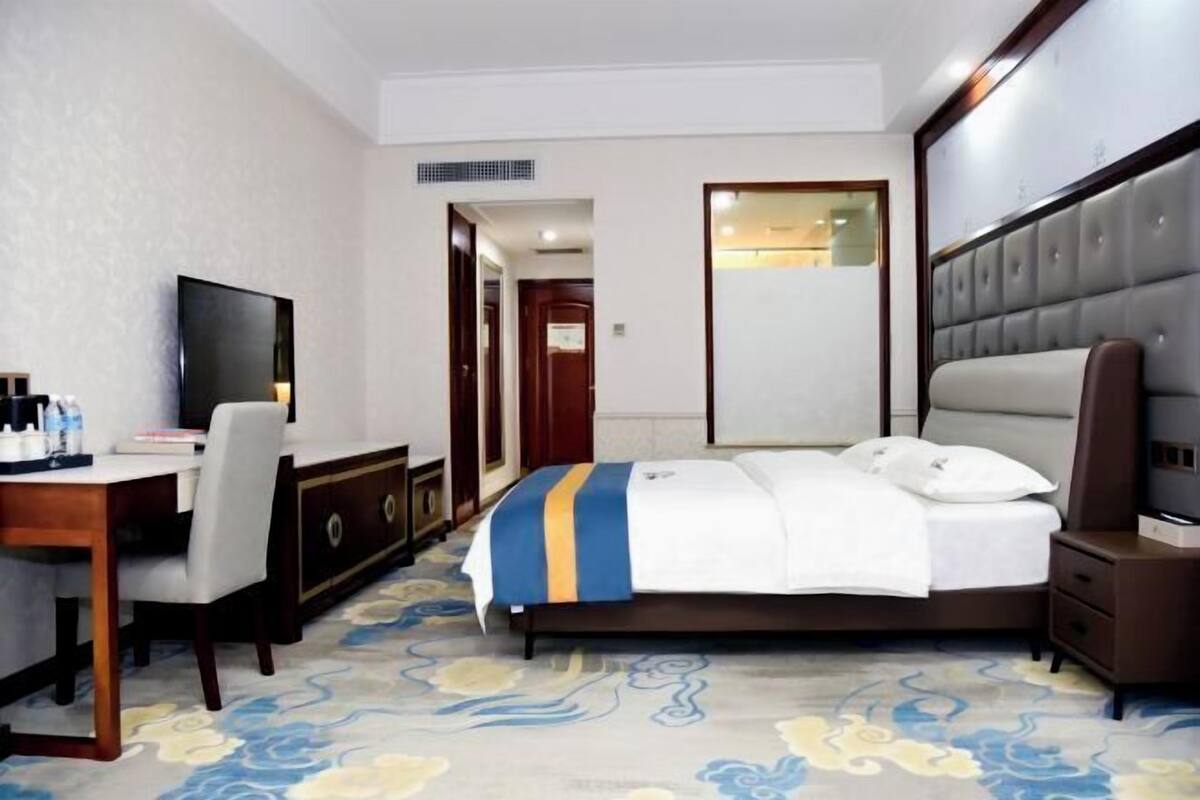 Una habitación de hotel con cama, escritorio, televisor y armario.
