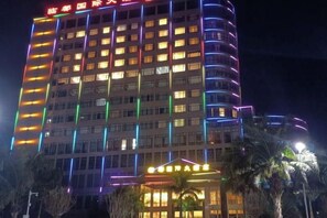Un hotel de varios pisos con ventanas iluminadas y una entrada bien iluminada.