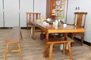 A wooden dining table with benches, a bookshelf, and a small plant. - Zhenkang Loisse International Hotel (Zhenkang)
