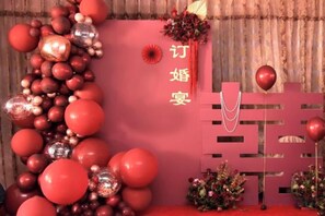 Decoración con temática roja, un arreglo vertical de globos y una pared decorativa.