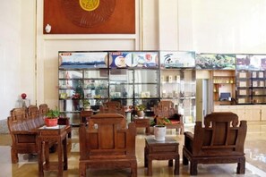 A lobby with wooden furniture, glass display cases, and a large wall decoration.