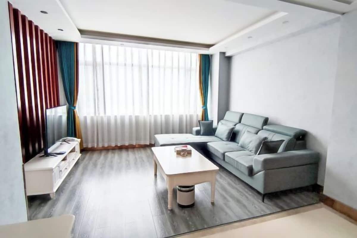 Una sala de estar moderna con un sofá gris, una mesa de centro blanca y un mueble para televisión.