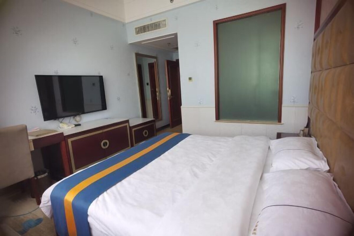 Una habitación de hotel con cama, escritorio, televisor y armario.