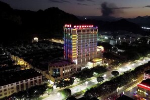 A multi-story hotel with a prominent central tower, surrounded by a well-lit urban area with visible roads and buildings. - Zhenkang Loisse International Hotel (Zhenkang)