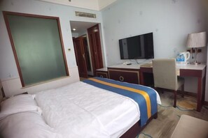Una habitación de hotel con cama, escritorio, televisor y una silla.