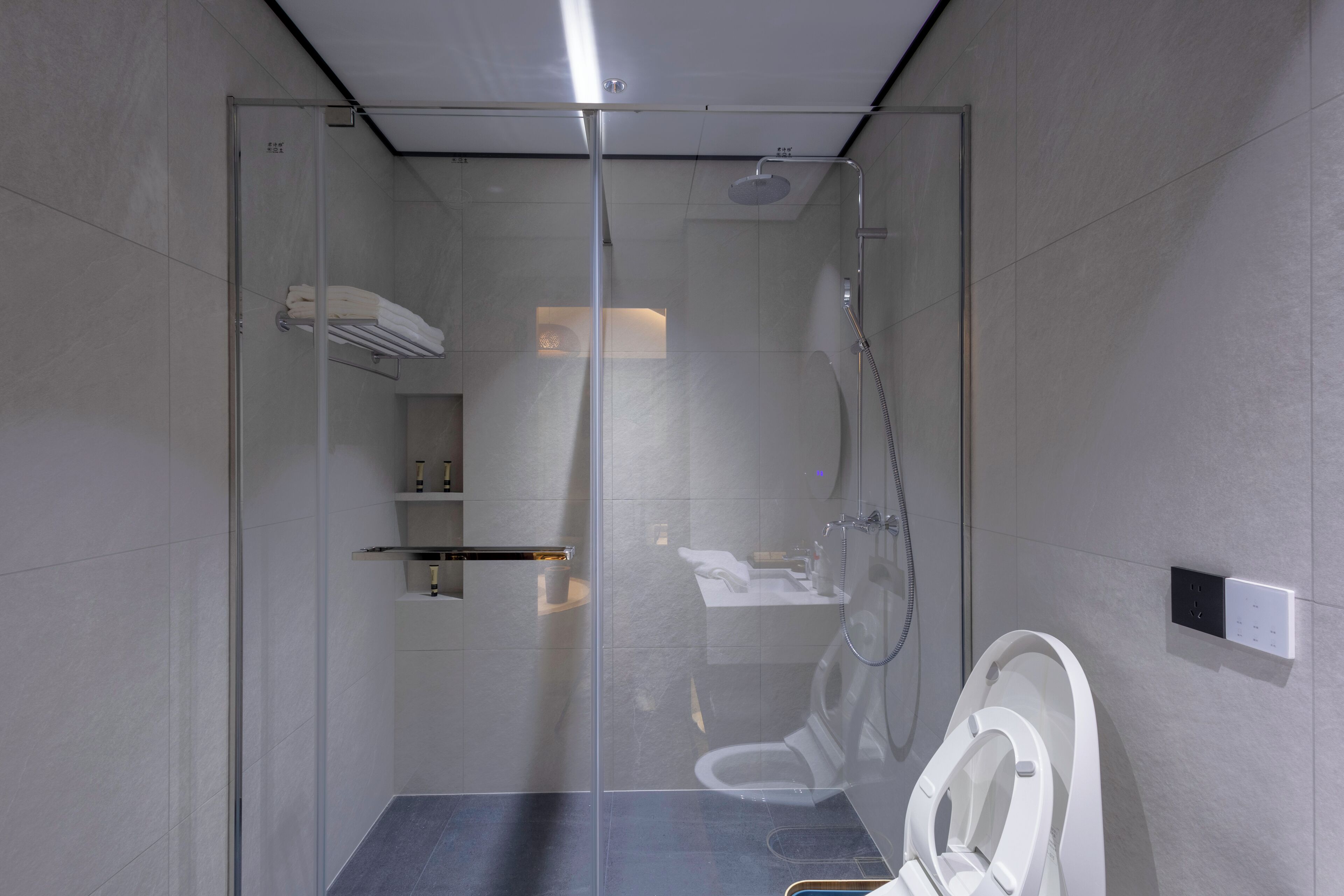 Un baño moderno con ducha de mampara de vidrio, inodoro y lavabo.