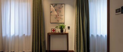 Una habitación con una consola de madera, una planta en maceta y un cuadro en la pared.