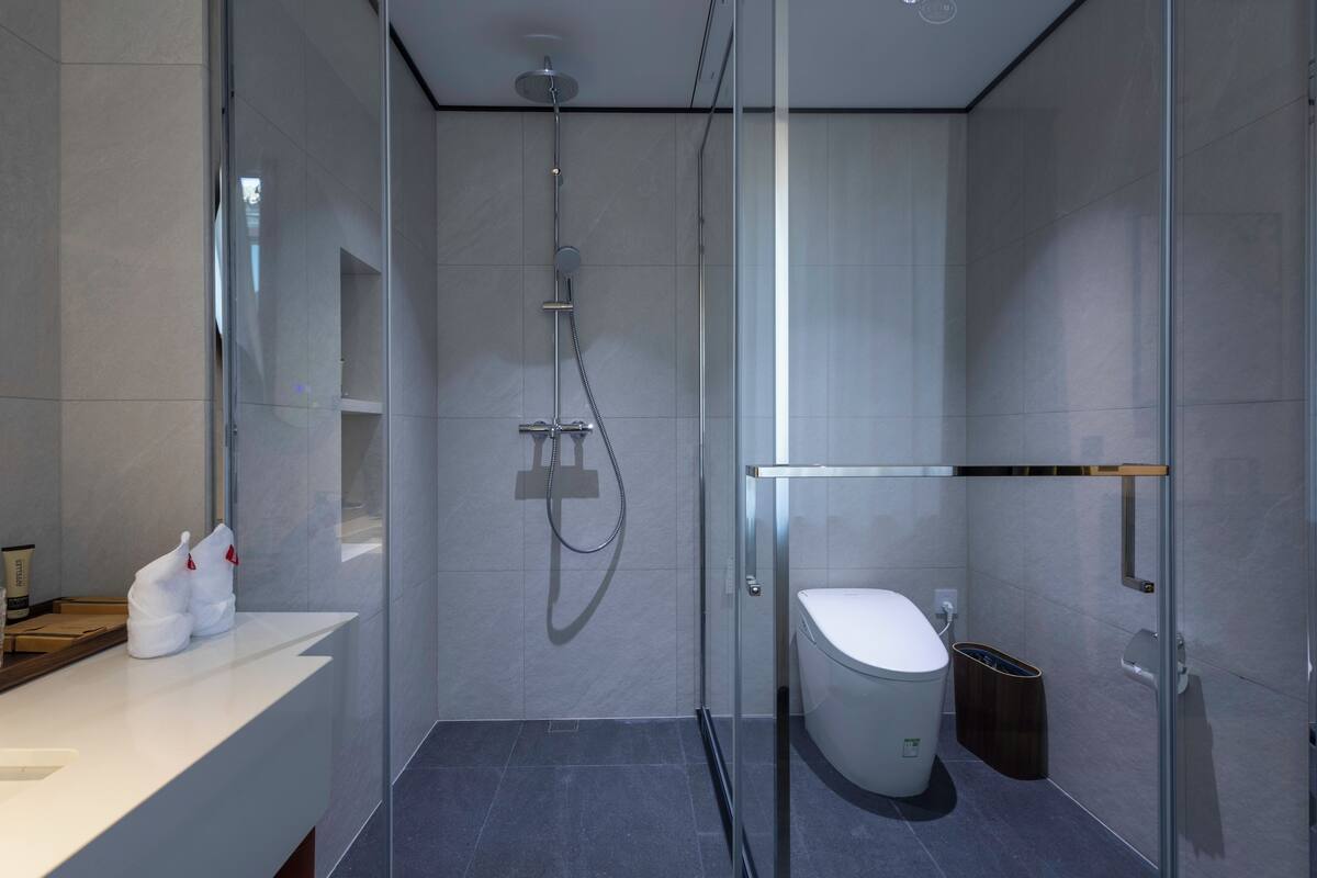 Une salle de bain moderne avec une douche à parois de verre, des toilettes blanches et un lavabo blanc agrémenté d’articles de toilette.