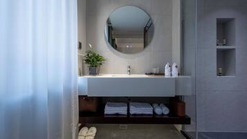 Un baño moderno con un espejo redondo, lavamanos blanco y estantes empotrados.