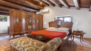 A bedroom with a large wooden wardrobe, a bed with ornate headboard, and a matching bench.