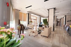 A spacious lobby with a modern design, featuring a large seating area, a reception desk, and a decorative horse statue. - Galaxy Bay Hotel (Yangxi)