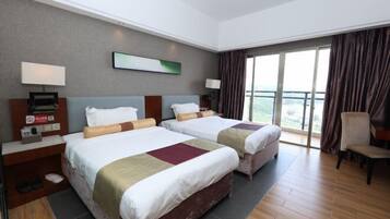 Habitación de hotel con dos camas, un ventanal con cortinas, una silla y vistas al exterior.