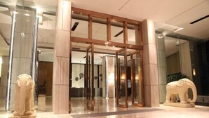 A modern hotel entrance with a glass door, wooden pillars, and two elephant sculptures. - Galaxy Bay Hotel (Yangxi)