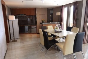A modern dining area with a marble table and contemporary chairs, a kitchen with dark cabinets, and a view of the outdoors through large windows. - Galaxy Bay Hotel (Yangxi)