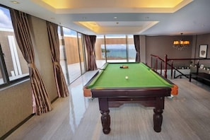 A pool table in a room with large windows and a view of the sea. - Galaxy Bay Hotel (Yangxi)
