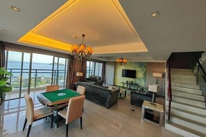 Amplia sala de estar con mesa de billar, asientos cómodos, televisor y una escalera.