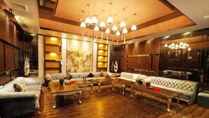A spacious lounge area with multiple seating options, including sofas and armchairs, arranged around a central coffee table. - Galaxy Bay Hotel (Yangxi)