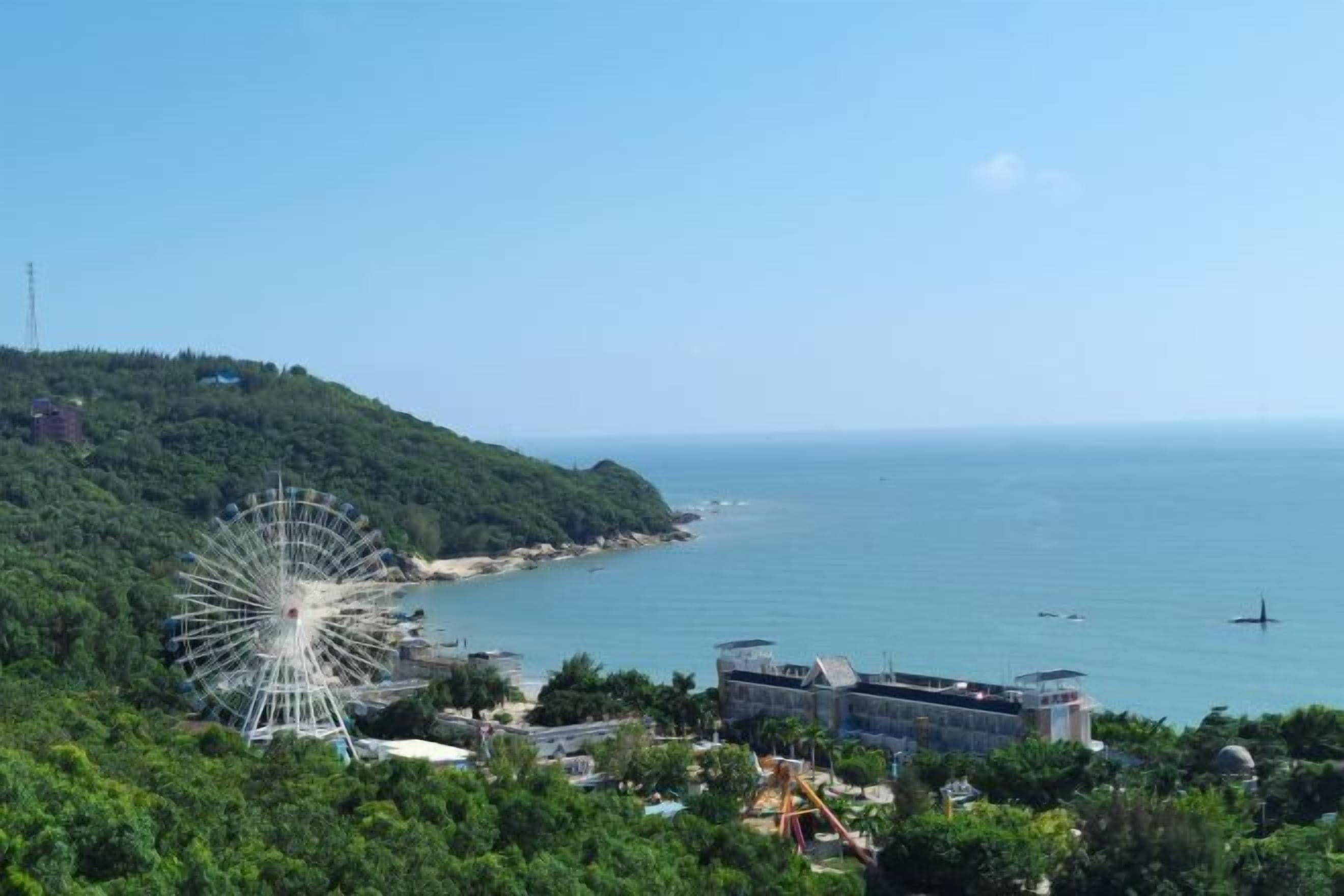 Una zona costera con una noria grande, una playa y un edificio con cúpula.