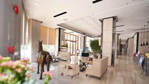 A modern lobby with a large glass wall, a horse sculpture, and a reception desk. - Galaxy Bay Hotel (Yangxi)