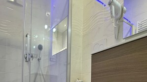 A modern bathroom with a glass shower enclosure, a white toilet, and a wooden vanity. - Turati Inn (Rome)