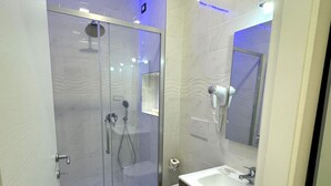 A modern bathroom with a glass-enclosed shower, a toilet, and a sink with a vanity. - Turati Inn (Rome)