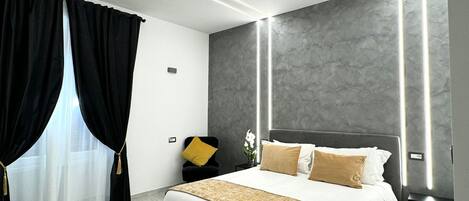 A modern bedroom with a large bed, a nightstand, a lamp, and a window with curtains.