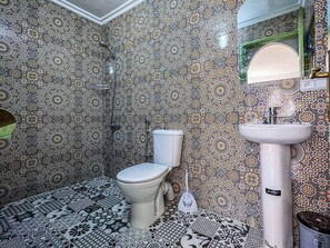 A bathroom with patterned tiles, a toilet, a sink, and a shower. - Cozy Ensuite Room with AC

 (Tangier)