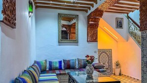 A Moroccan-style living room with a sofa, a coffee table, and a decorative mirror. - Cozy Ensuite Room with AC

 (Tangier)