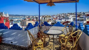 A terrace with wicker furniture and a view of a cityscape. - Ensuite Room in Tangier Medina

 (Tangier)