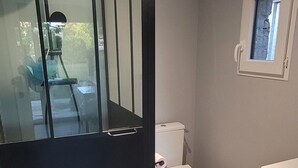 Un baño moderno con cabina de ducha, inodoro y un ventanal.