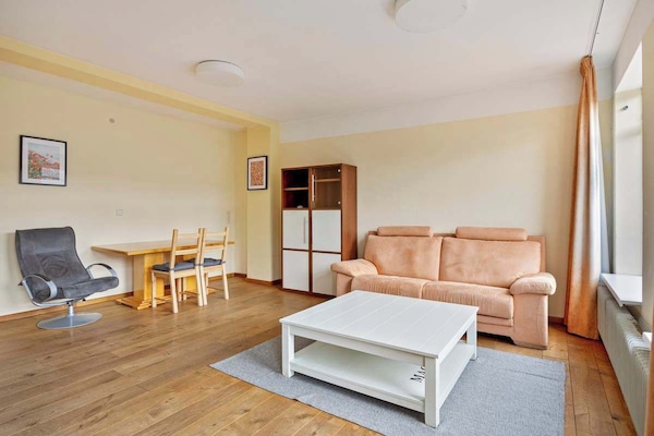 Living room with a peach sofa, white coffee table, and wooden dining set on hardwood floors.
