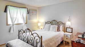 Un dormitorio con cama, mesita de noche, lámpara y un armario pequeño.