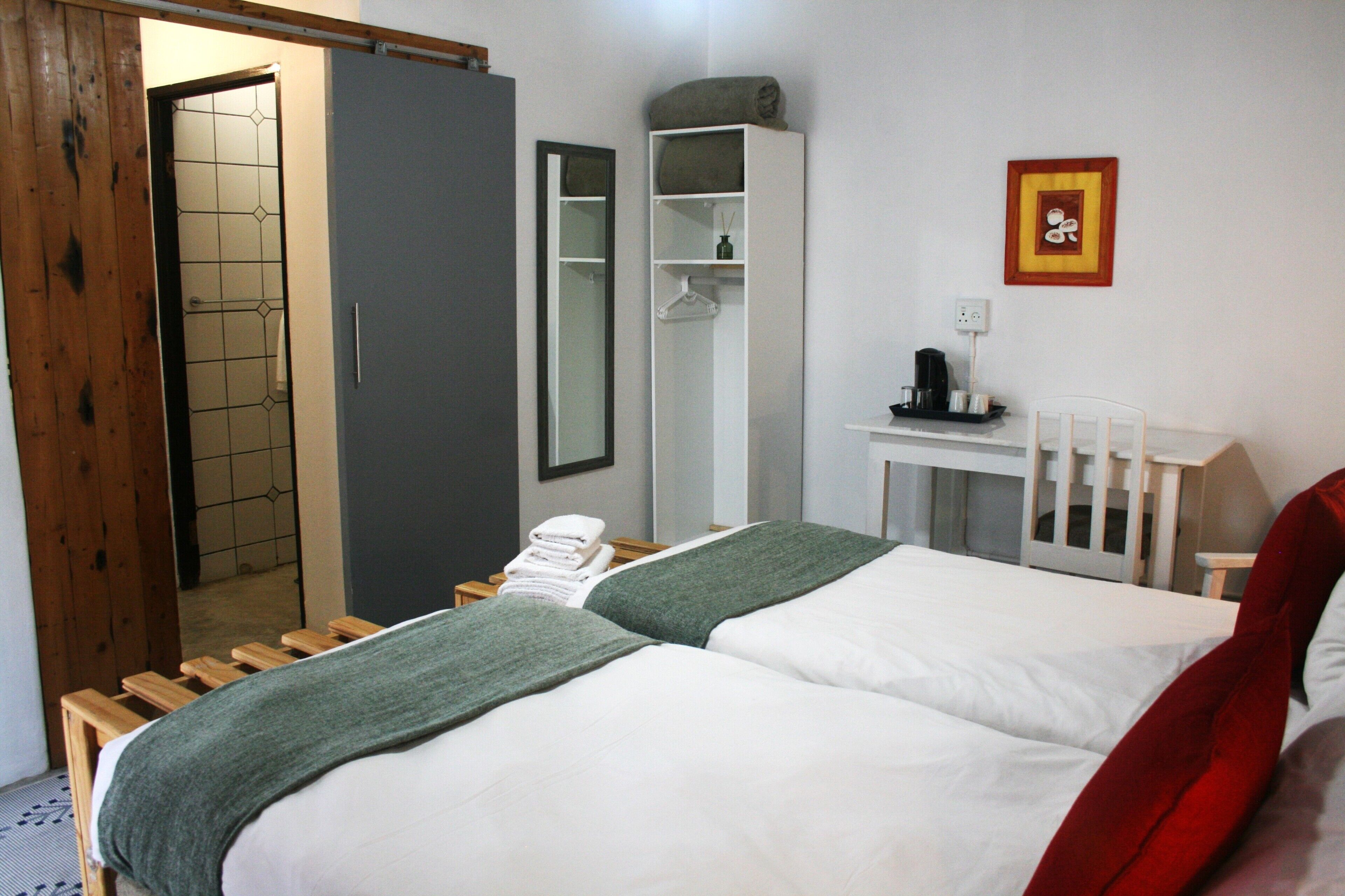 Een hotelkamer met een bed, een kledingkast, een bureau en een spiegel.