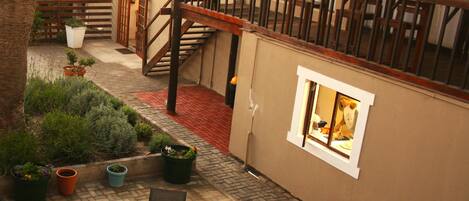 Un patio al aire libre con una mesa, sillas, una escalera y plantas en macetas.