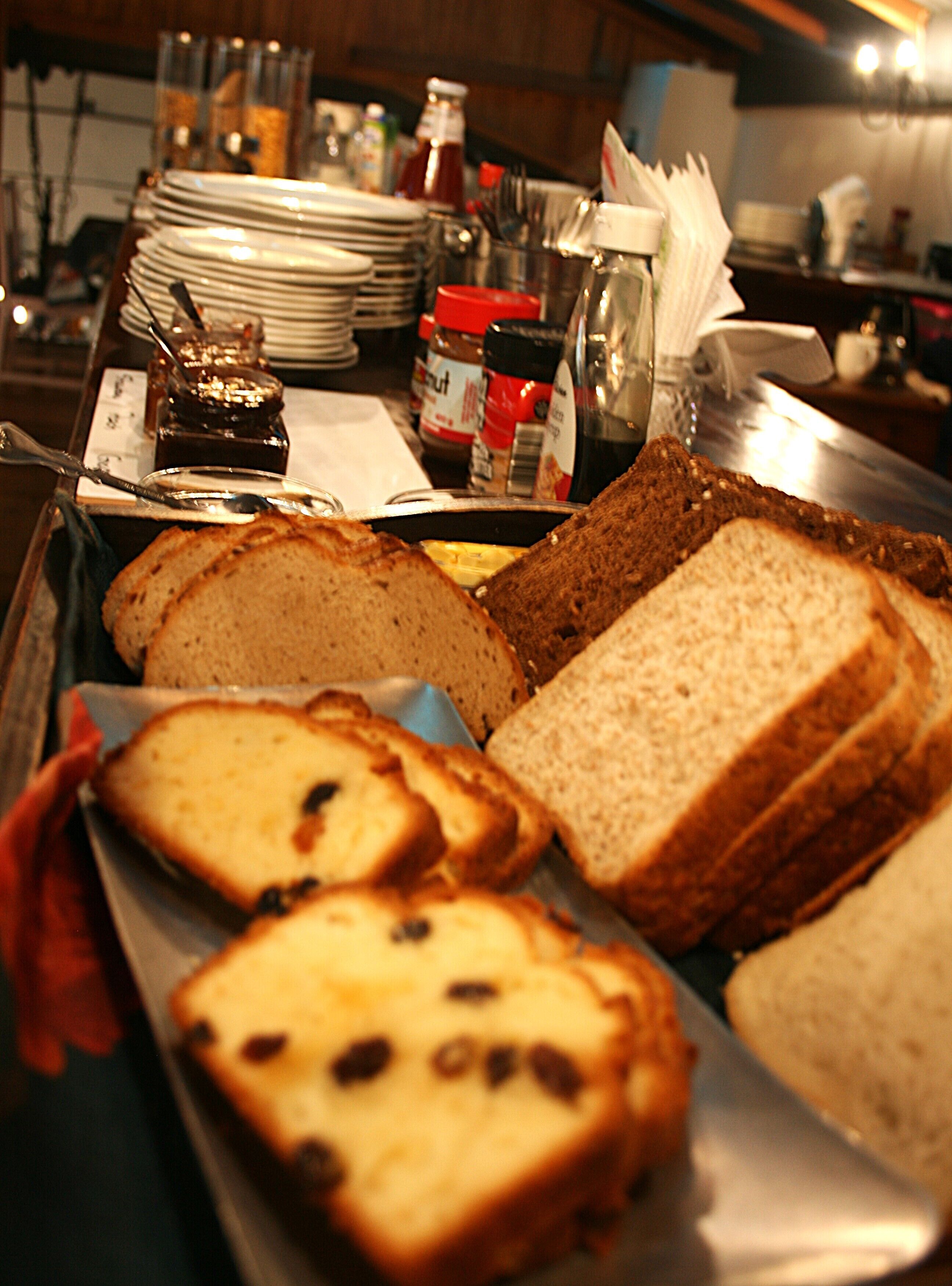 A variety of breads on a tray, including whole grain and white bread, in a kitchen setting.