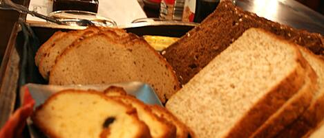 A variety of breads on a tray, including whole grain and white bread, in a kitchen setting.