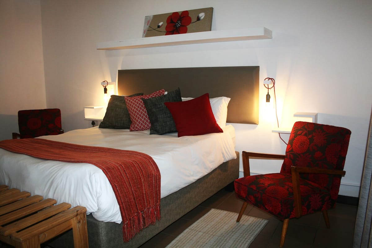 Una habitación de hotel con una cama, una silla, un escritorio y una lámpara.